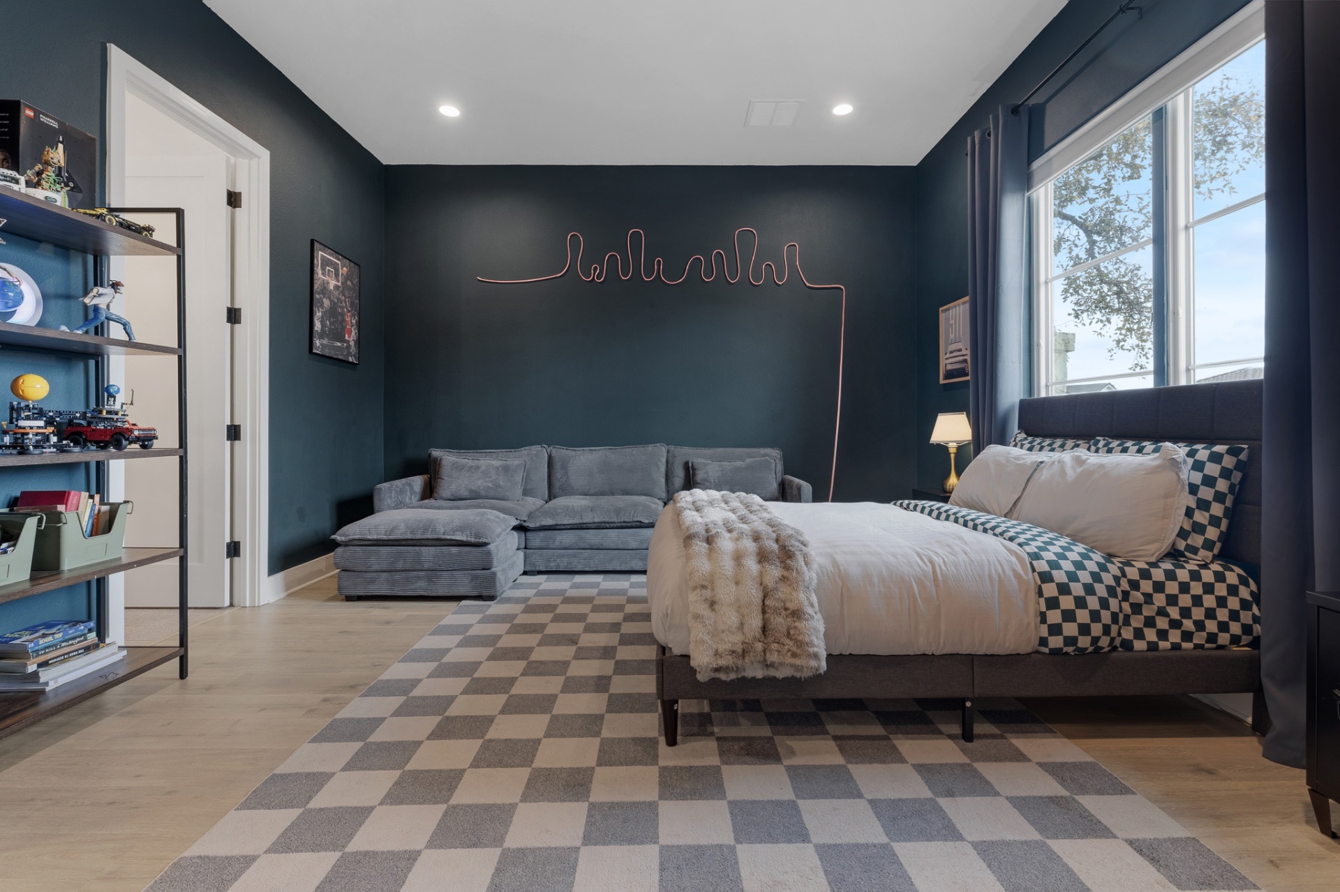 Bedroom 3 wide with neon wall art, checkered rug, sectional sofa and Lego shelving
