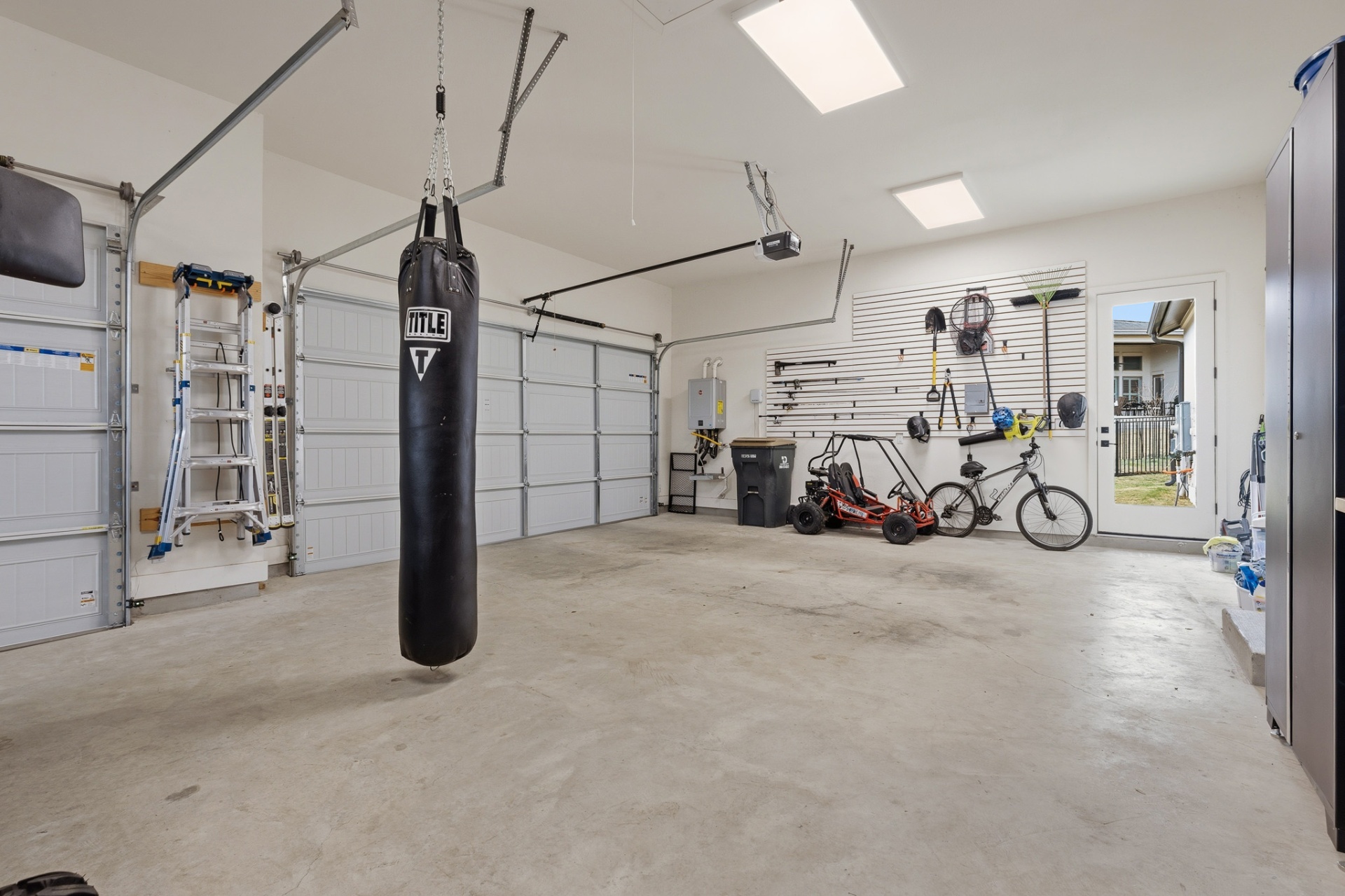 3-car garage interior — punching bag, slatwall organizer, go-kart, bike and backyard door
