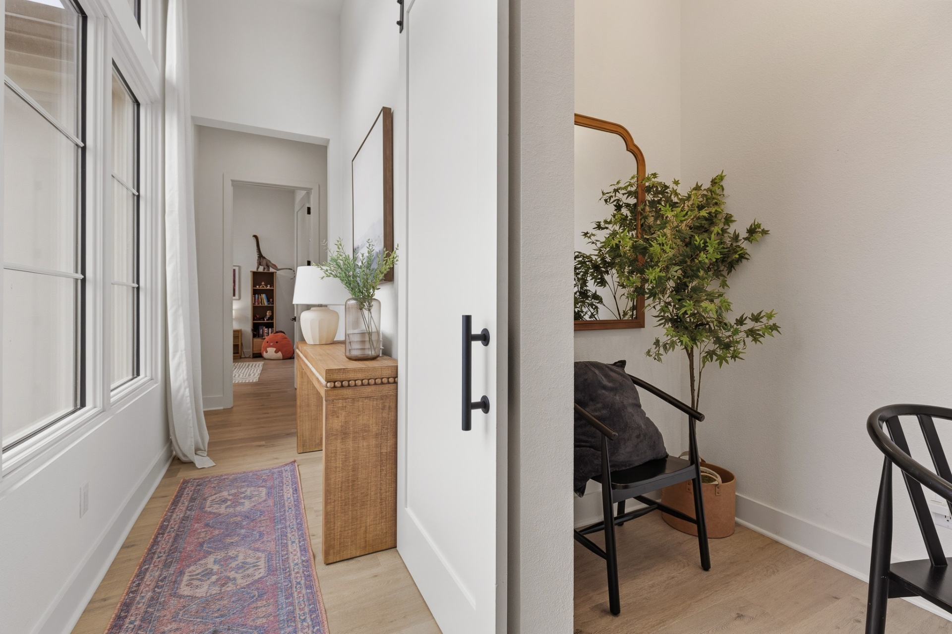 Entry hallway with barn door, wood console, runner rug and view to kids' wing