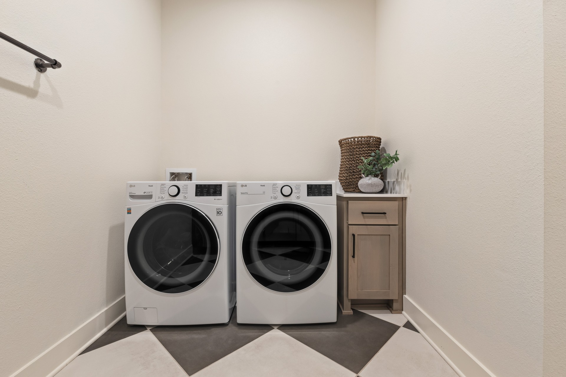 Laundry room with LG front-load washer and dryer, checkered tile floor and iron hanging rod