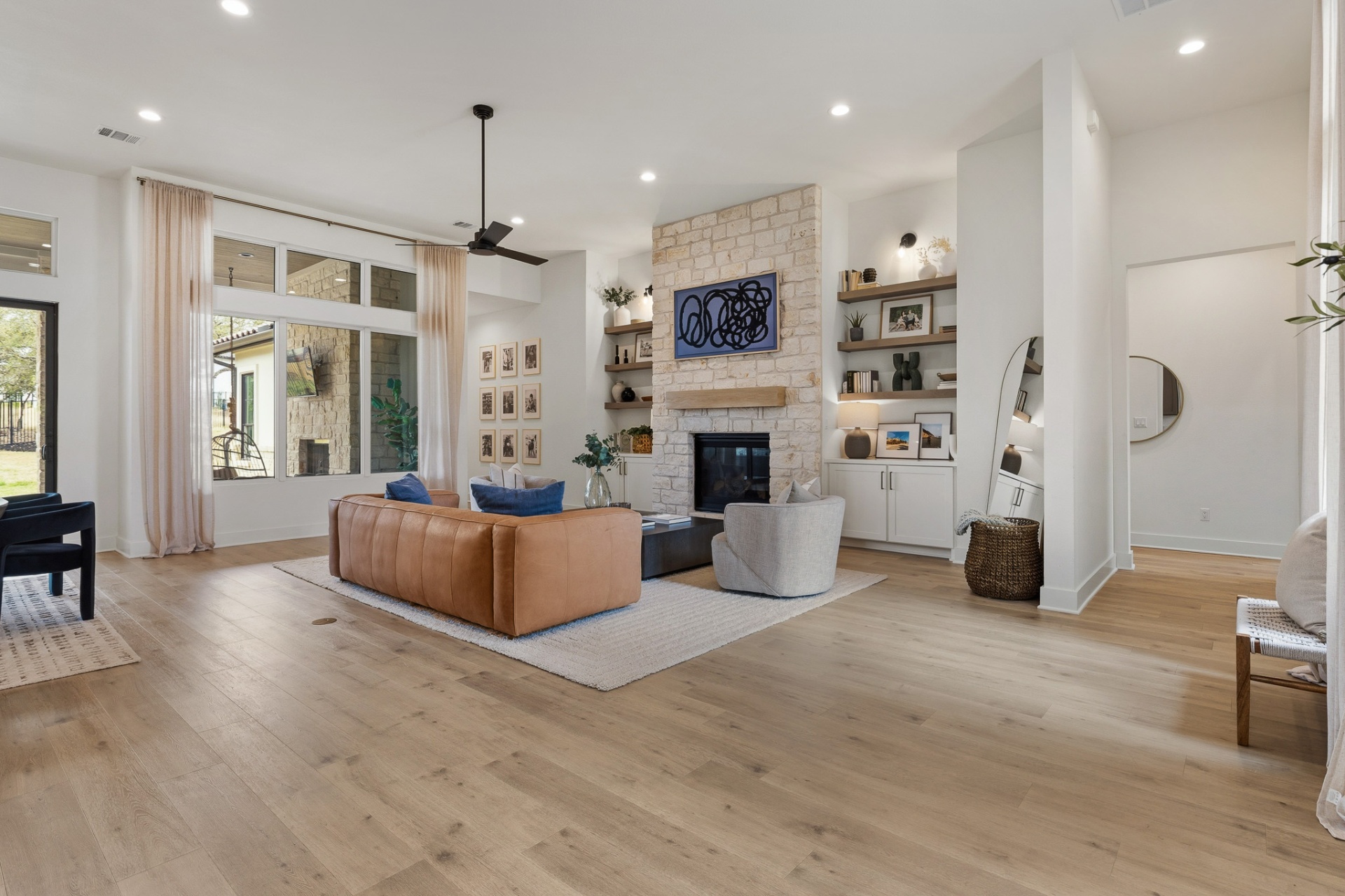 Living room super-wide — stone fireplace, patio doors, built-in shelving, leather sofa and entry hallway