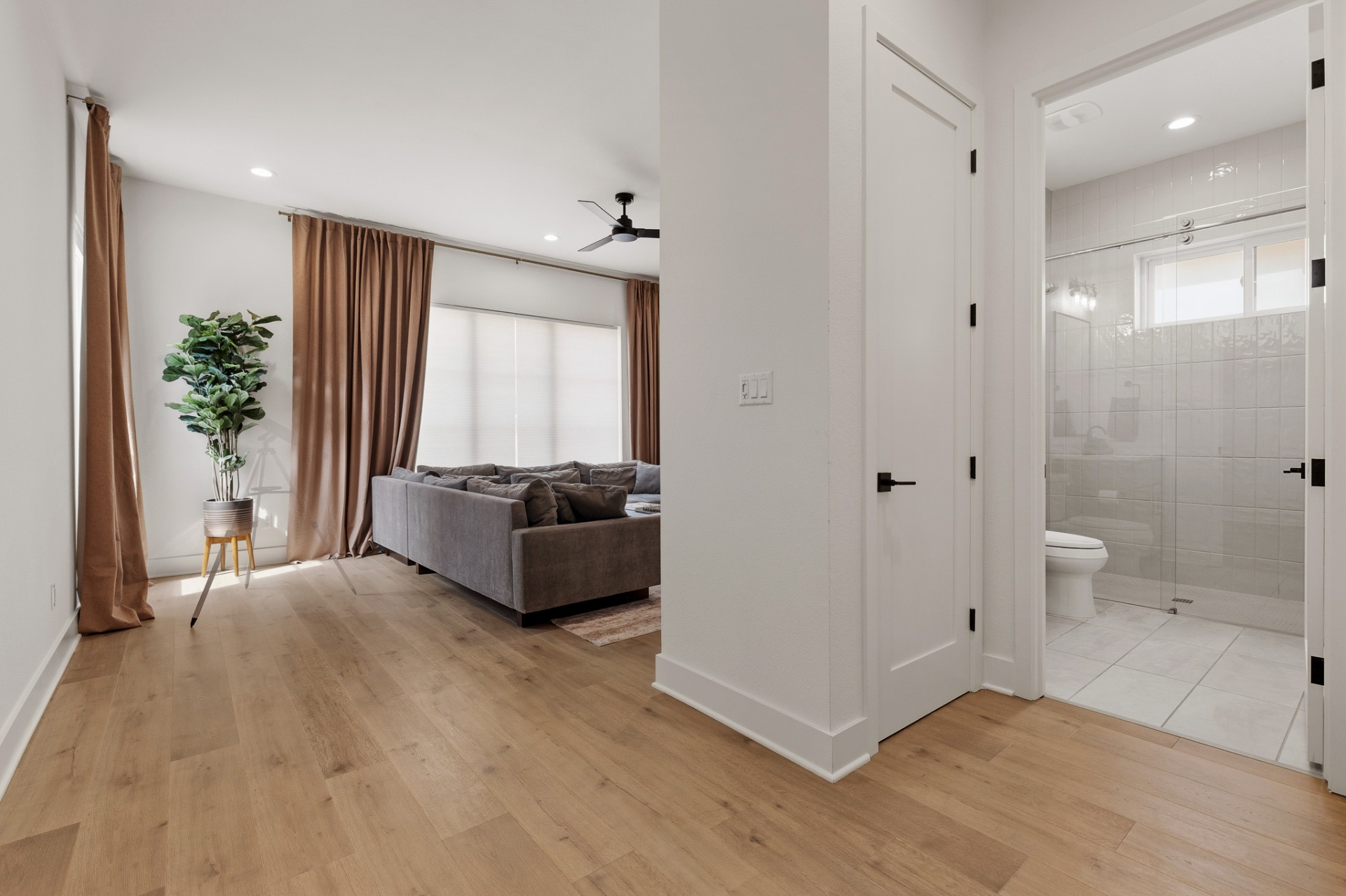 Media wing overview — game room seating area with adjacent full bathroom and glass shower