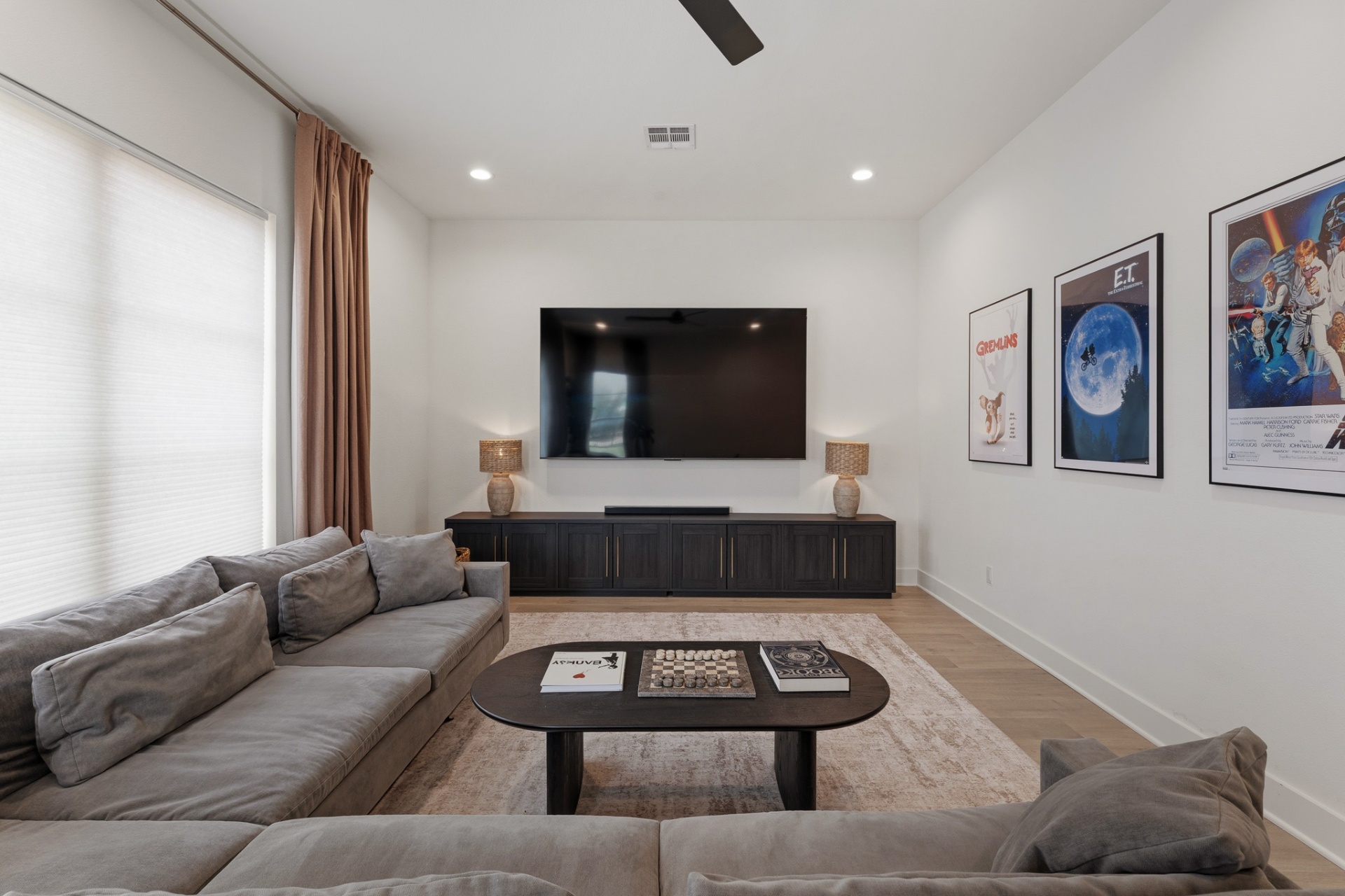 Media / game room — large-screen TV, dark entertainment console, Gremlins, E.T. and Star Wars posters