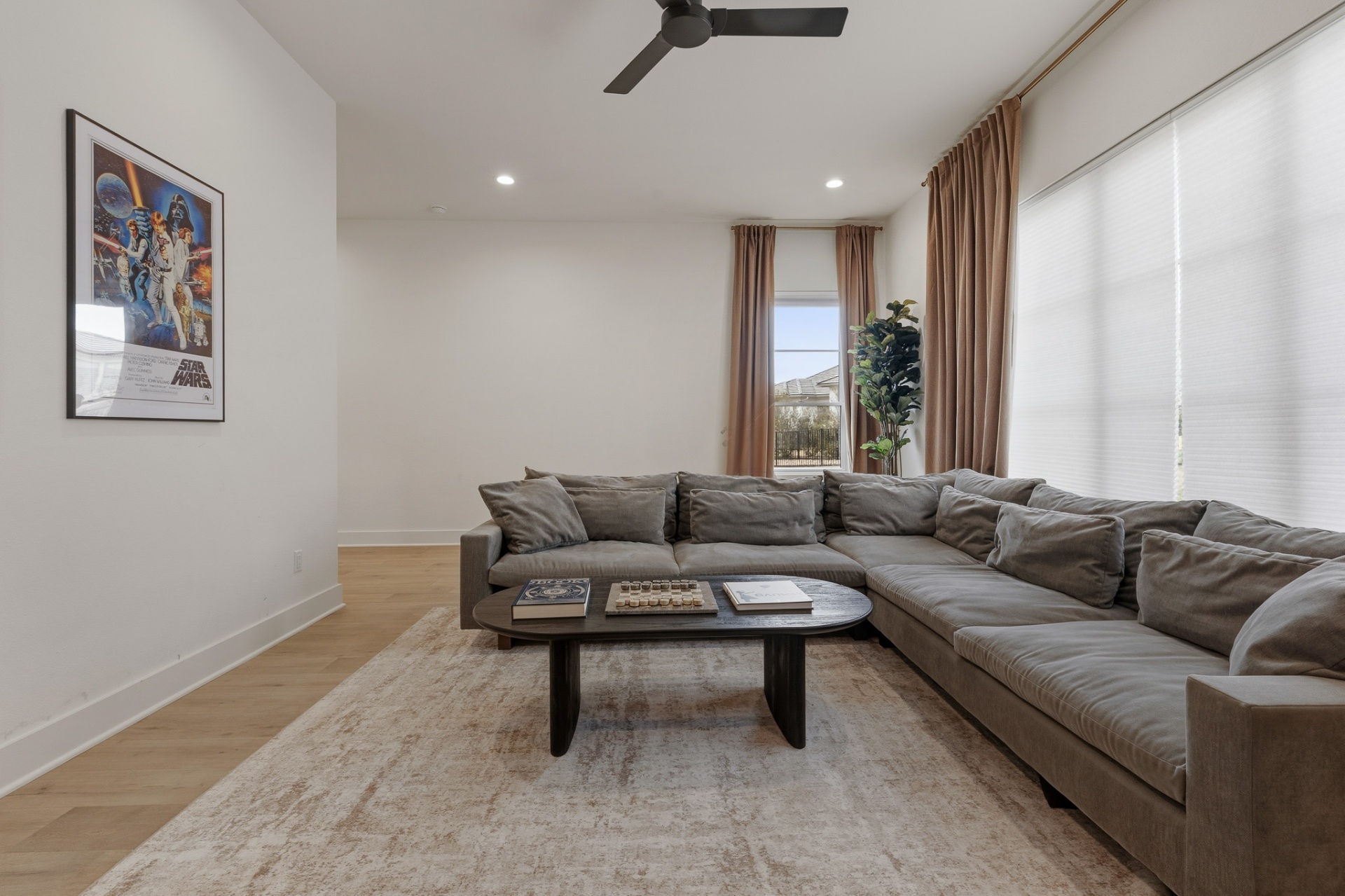 Media room sectional with Star Wars poster, coffee table and natural-light windows