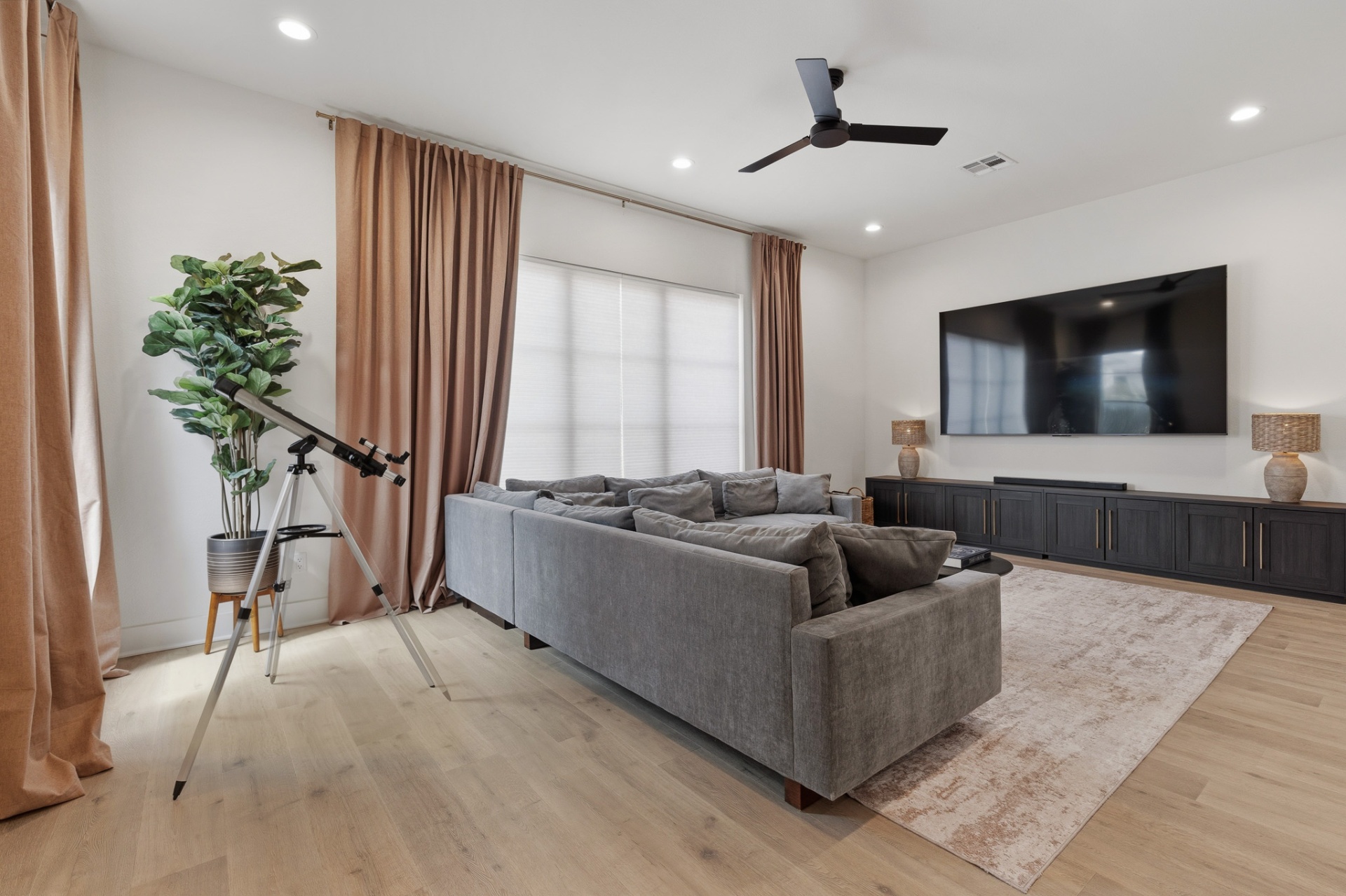 Media room wide with telescope, fiddle leaf fig, sectional sofa, TV and large windows
