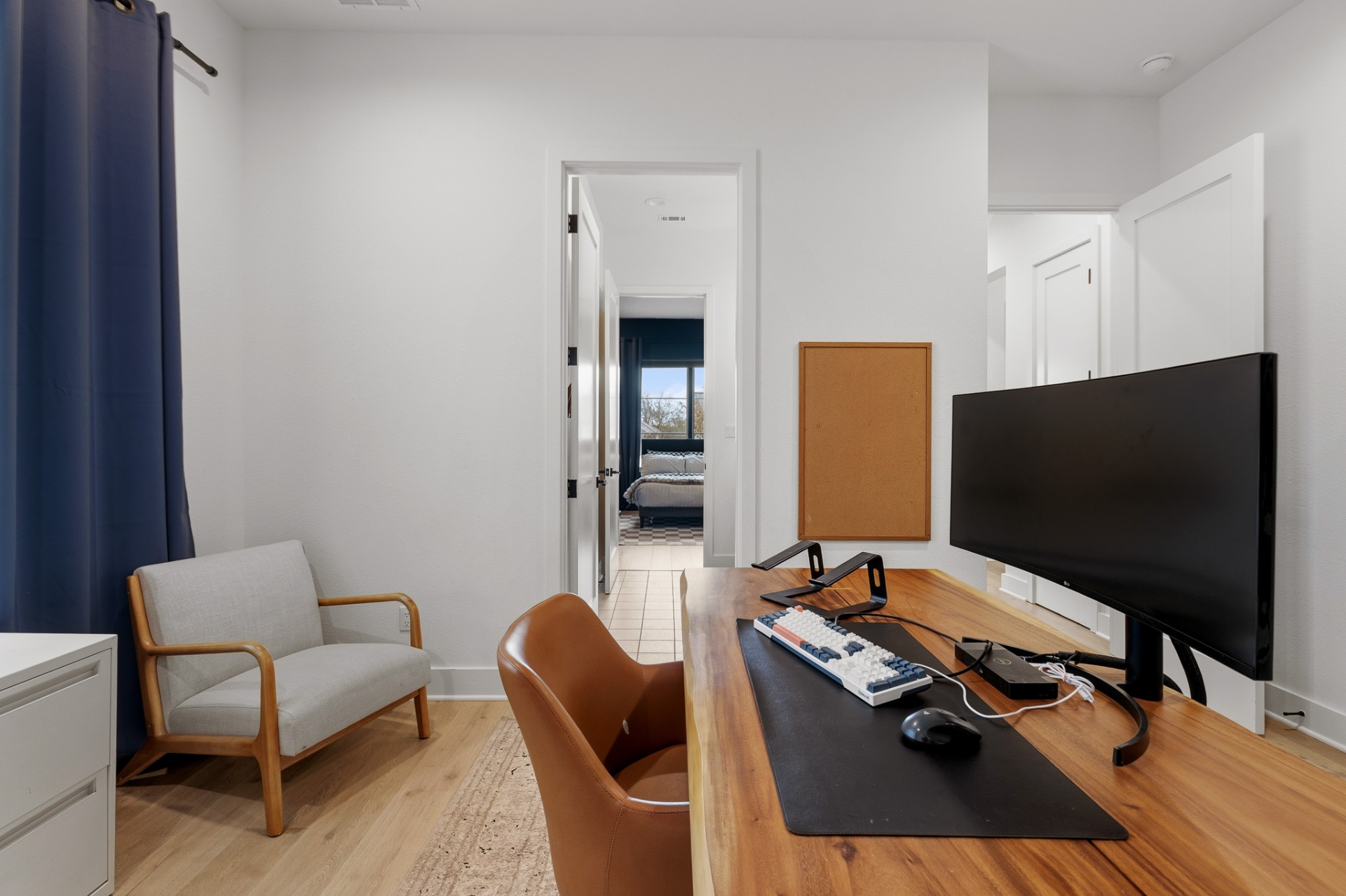 Home office angle view — live-edge desk, leather chair and view to adjacent bedroom