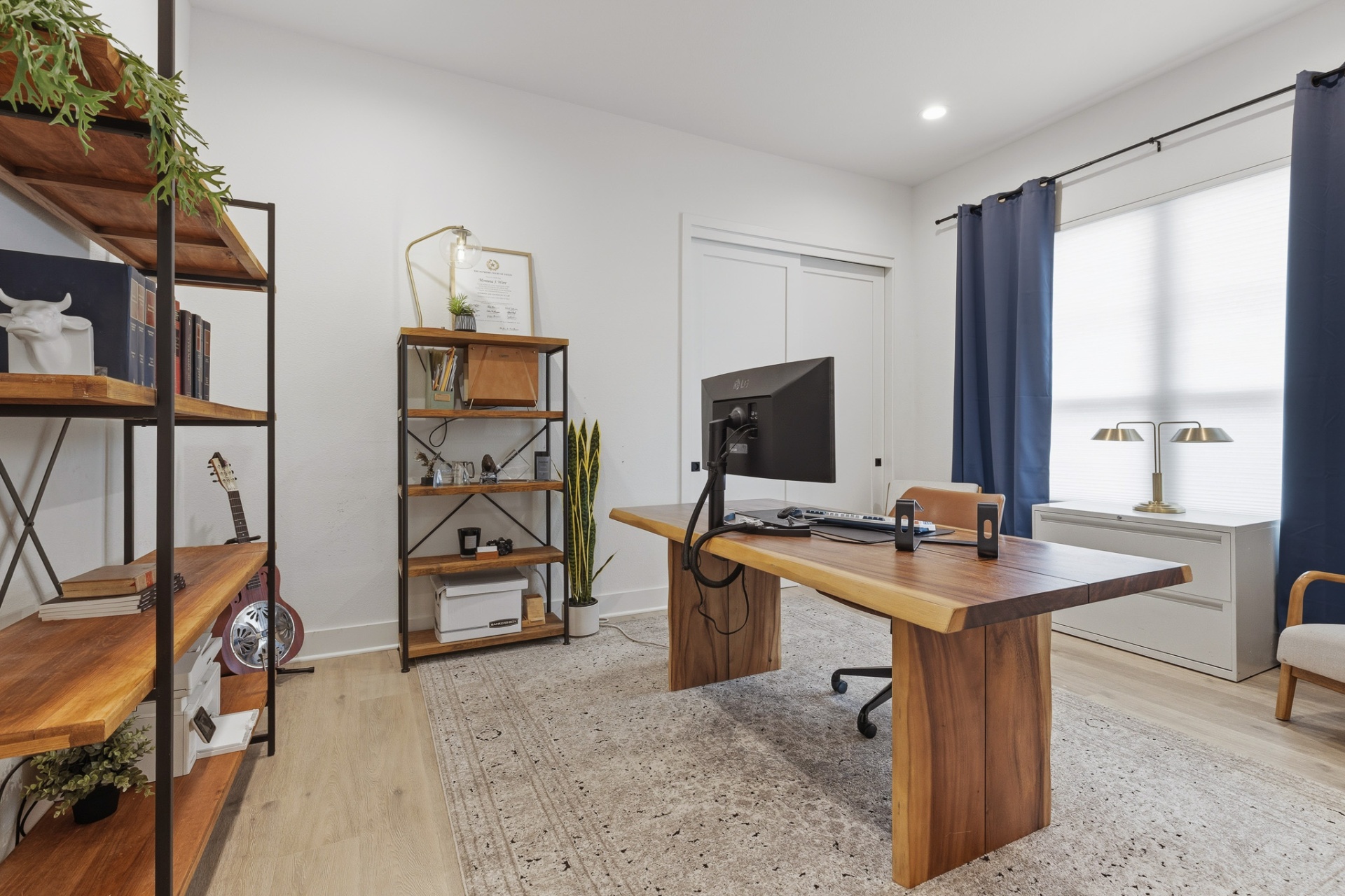 Home office with live-edge walnut desk, industrial bookshelves, guitar and dual monitors