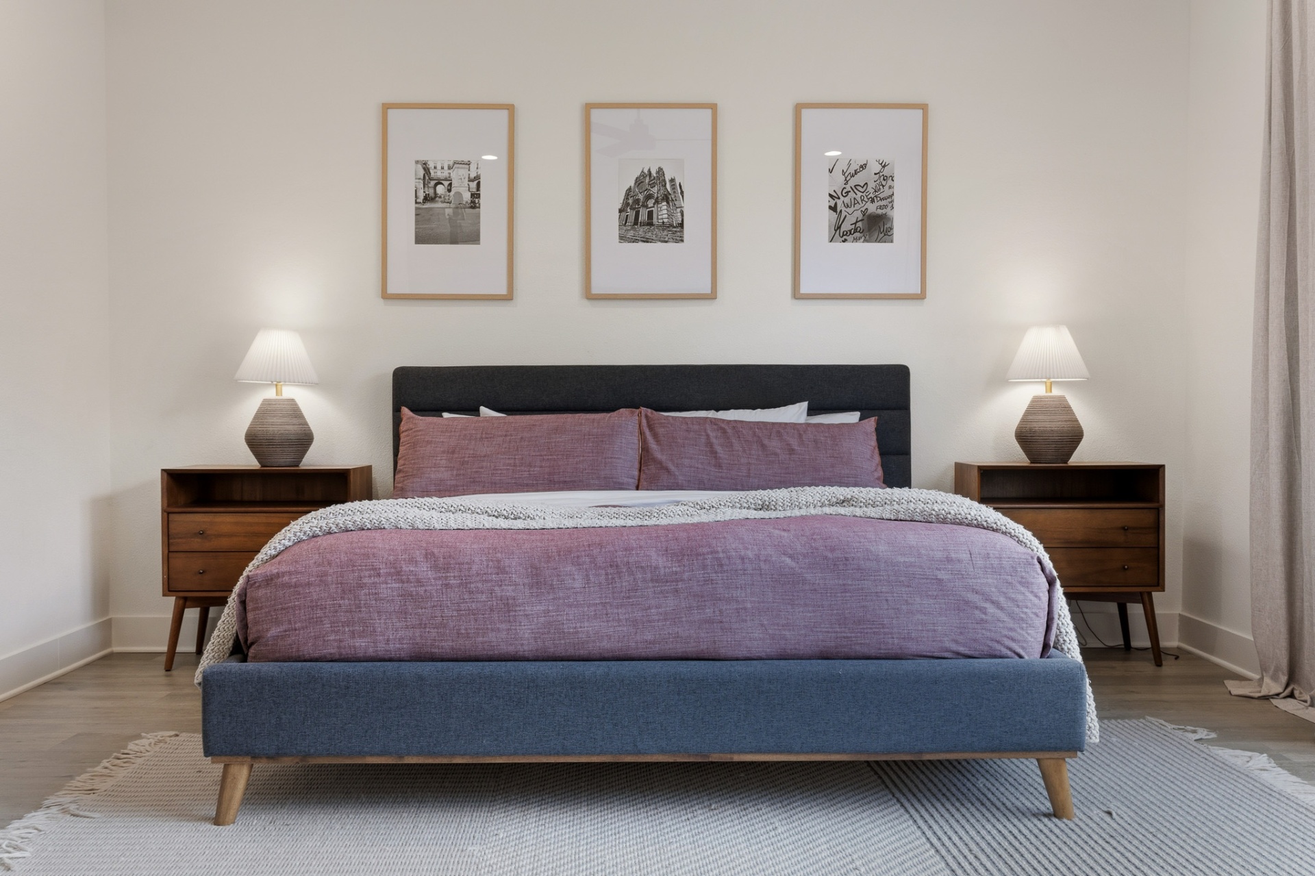 Primary bedroom bed close-up with tri-panel gallery wall and matching nightstands