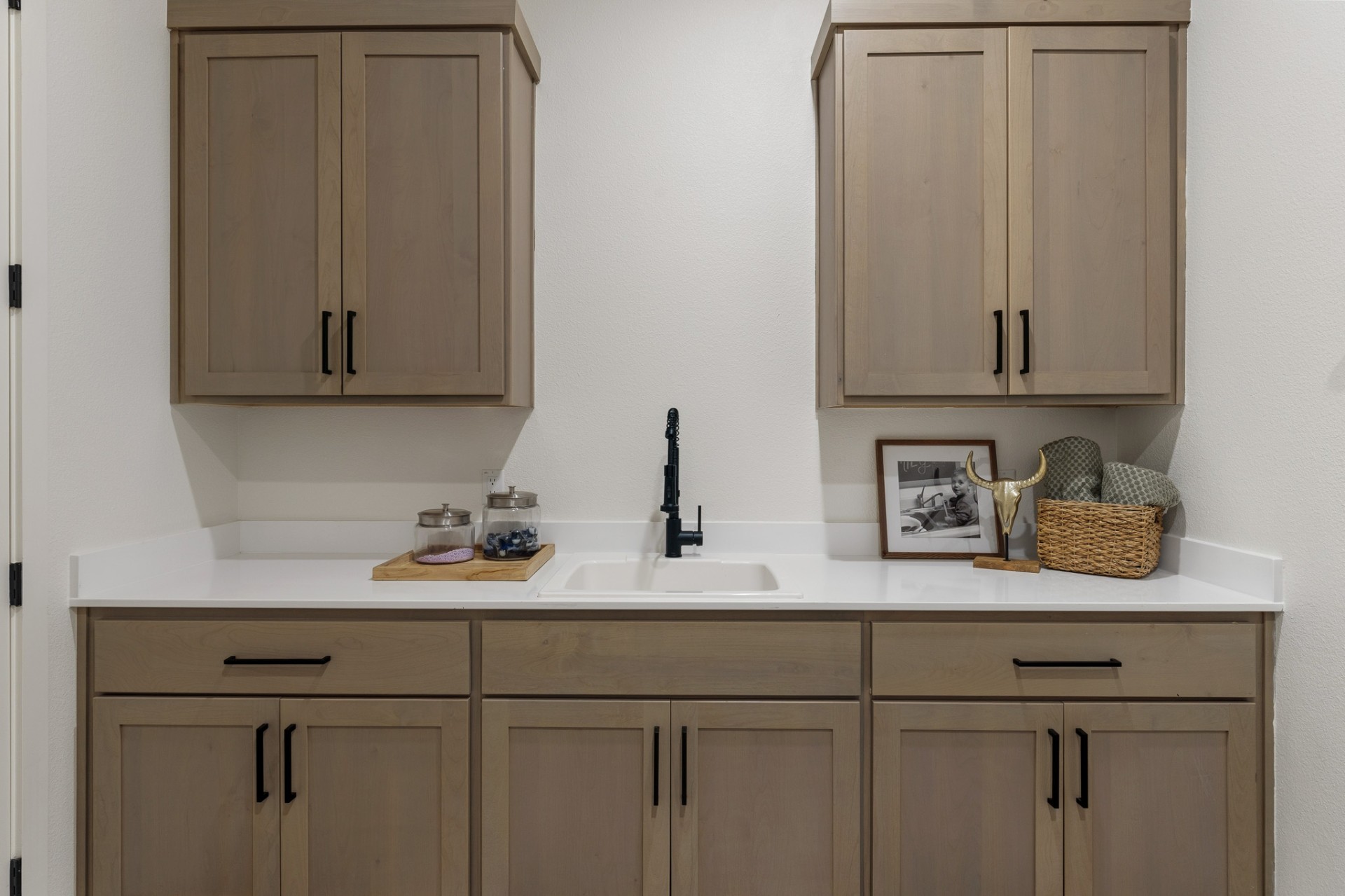 Utility/laundry room with tan shaker cabinets, quartz countertop and black pull-down faucet