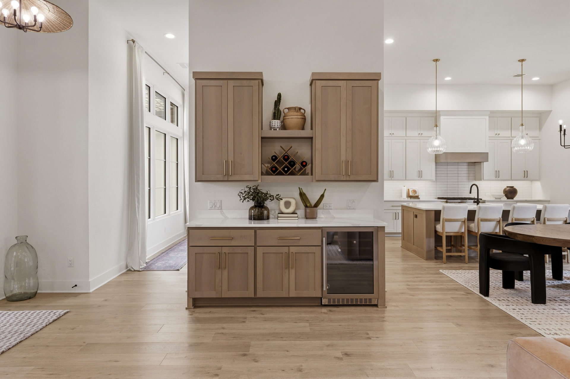Wet bar with tan shaker cabinets, wine fridge, open wine rack and view to kitchen and dining room